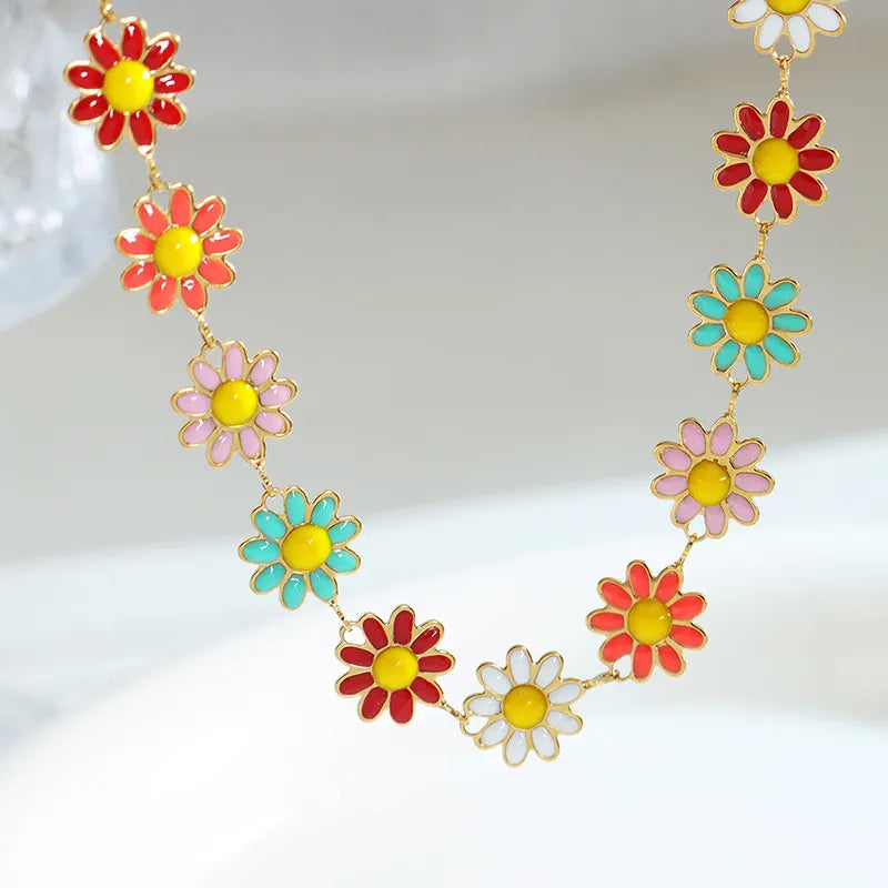 Gold metal bangle with colorful enamel flower charms, including red, pink, white, and teal blossoms.