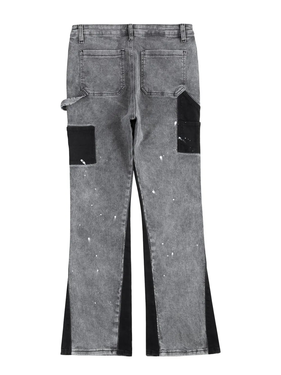 Dark gray bootcut jeans with black panels, paint splatters, and split hem