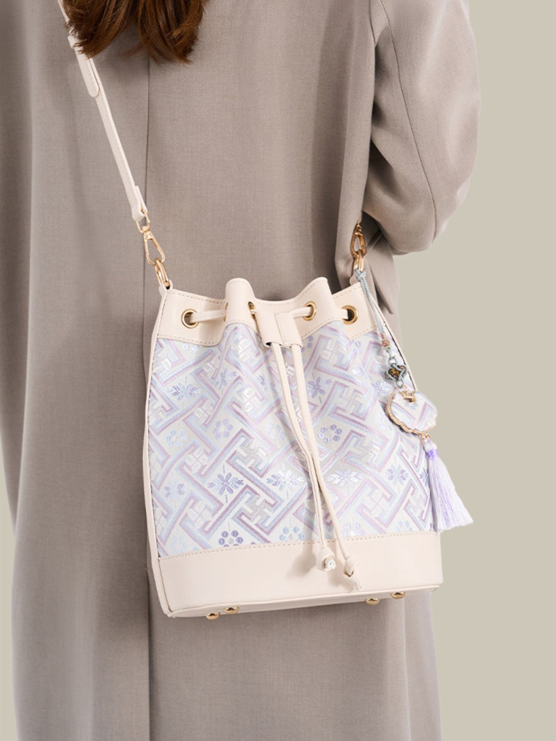 crossbody bag in cream featuring drawstring closure and bucket fit