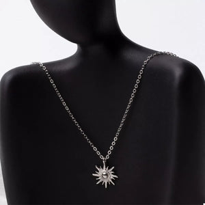 Silver sunburst pendant necklace with delicate chain and lace trim detail.