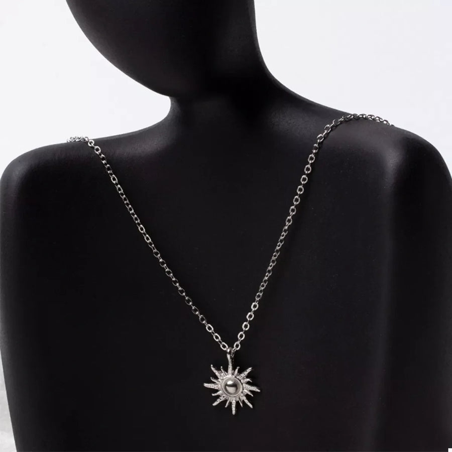 Silver sunburst pendant necklace with delicate chain and lace trim detail.