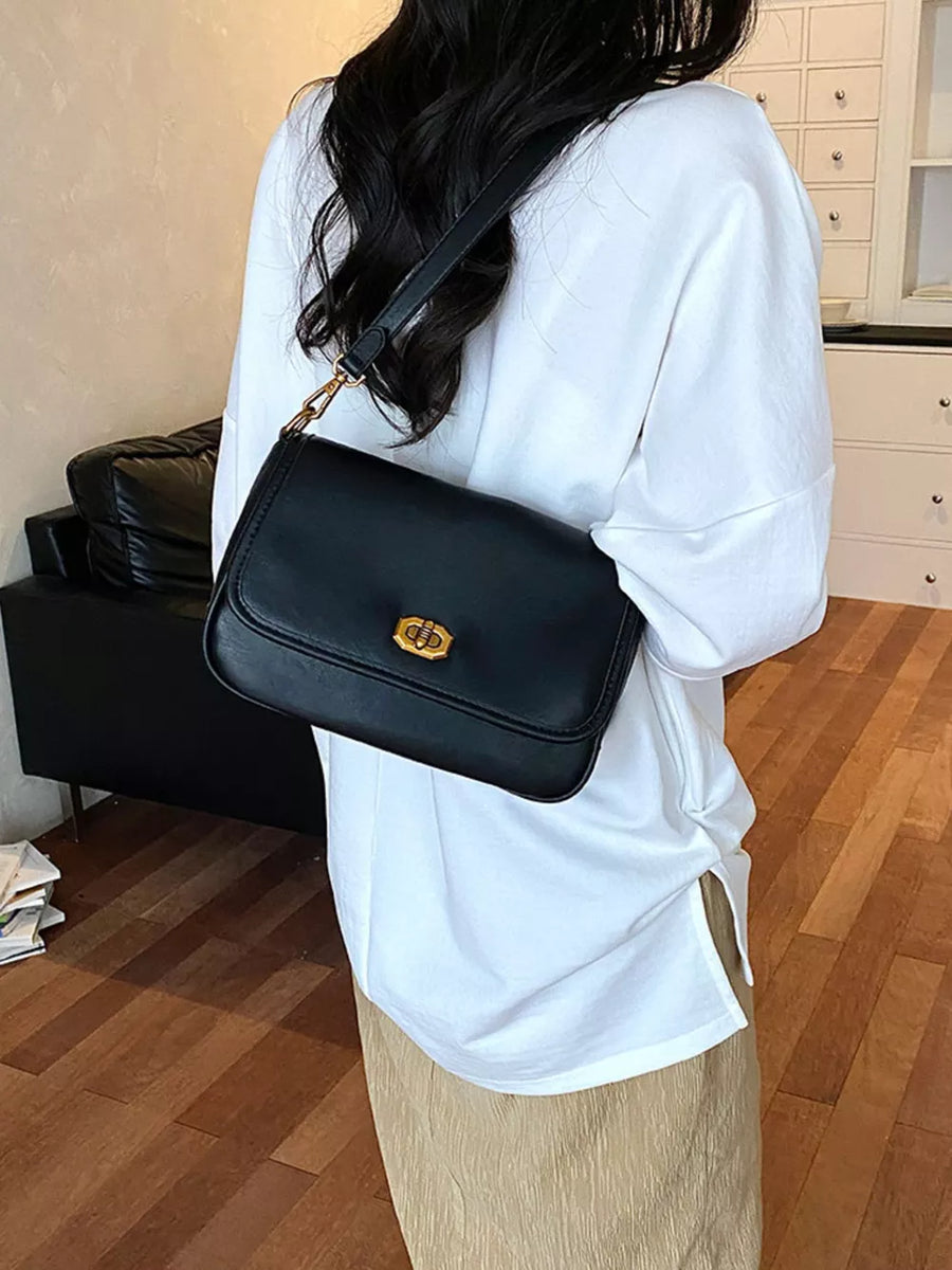 shoulder bag in black featuring flap closure and boxy fit