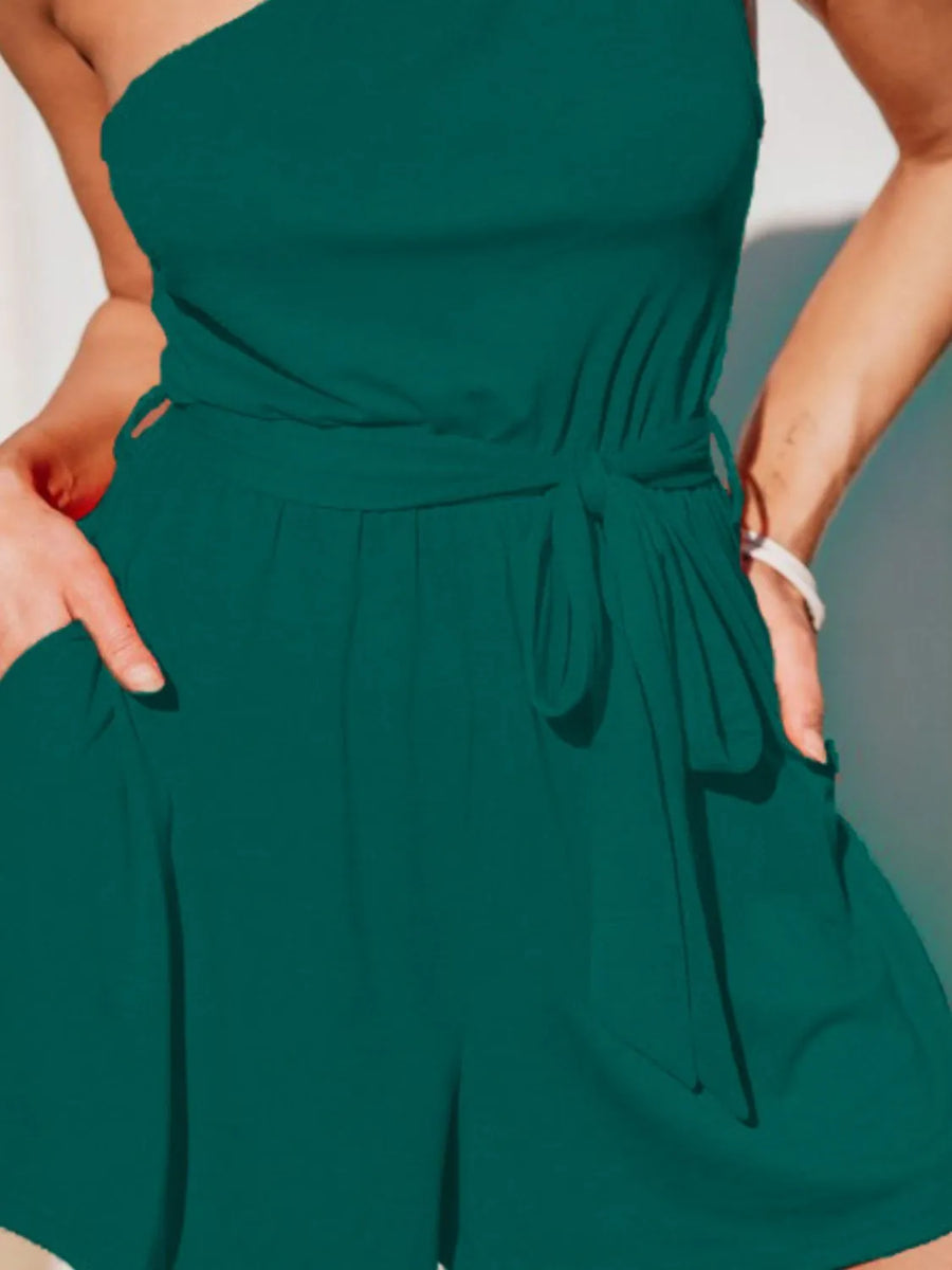 Dark green asymmetrical knot-waist romper with one-shoulder neckline and side pockets.