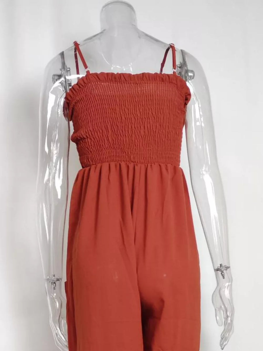 Orange-red smocked wide leg romper with spaghetti straps and pockets.
