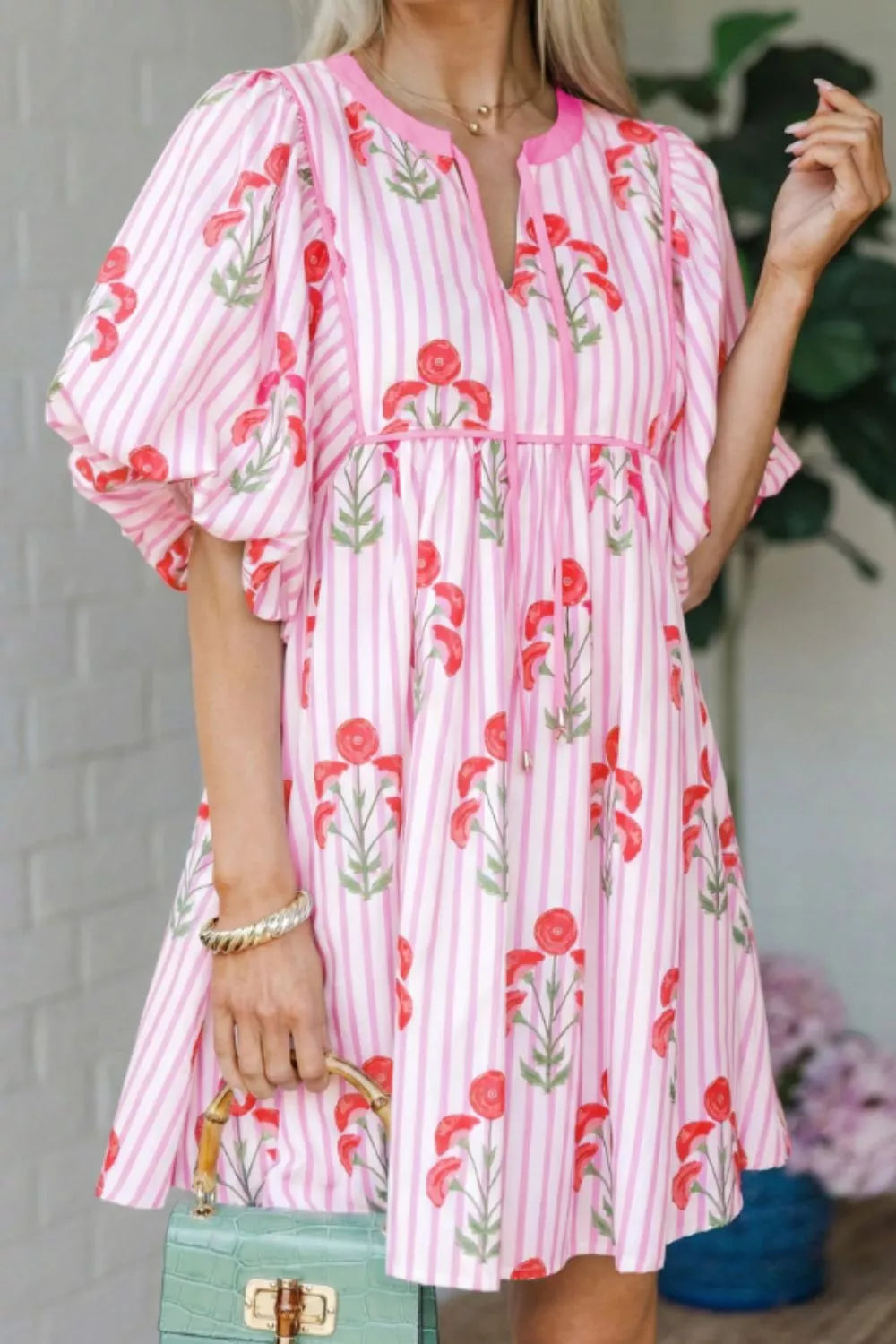 Floral stripe mini dress in blush pink with red floral print, puff sleeves, and tie detail.