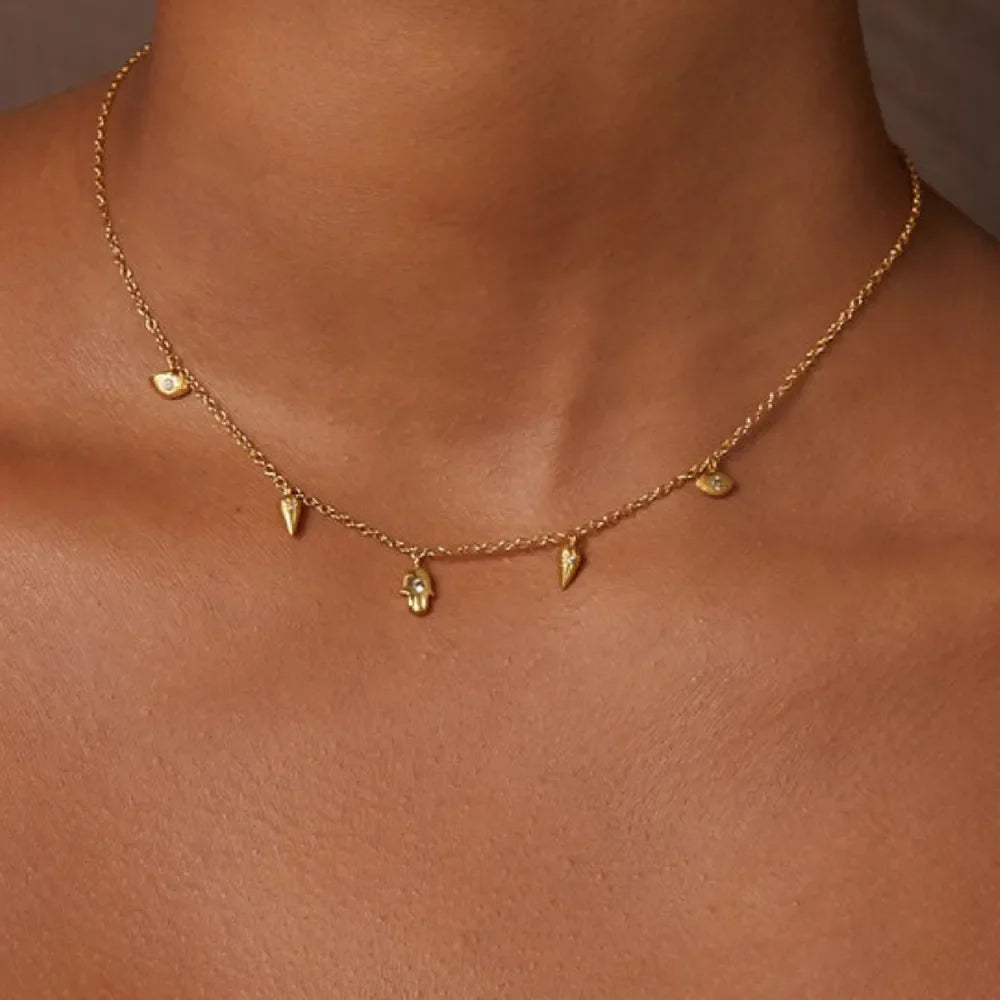 Gold layered necklace with spike, hamsa, and evil eye charms.