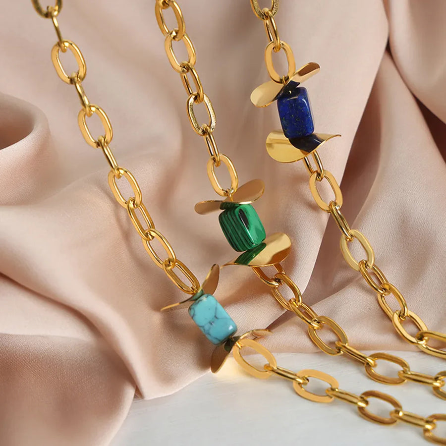 Geometric malachite pendant necklace with 18K gold-plated chain and blue, dark green, and light blue stones.