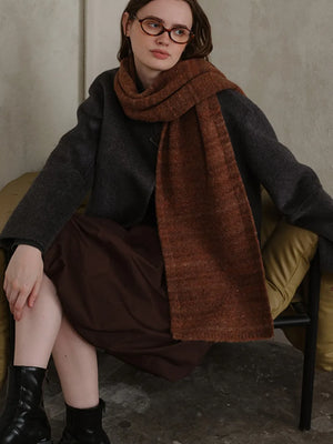 Textured mélange knit scarf in Terracotta, styled with a dark gray sweater and brown dress.