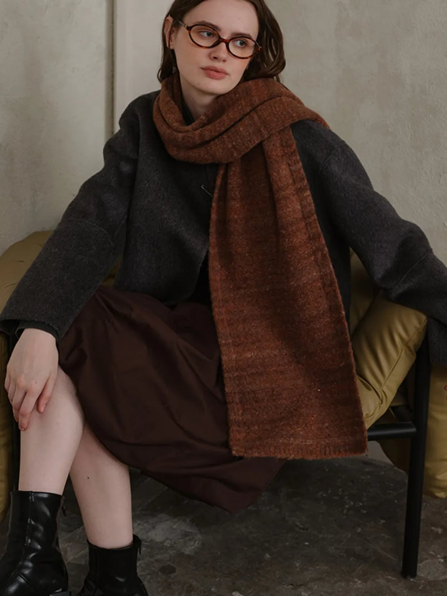 Textured mélange knit scarf in Terracotta, styled with a dark gray sweater and brown dress.