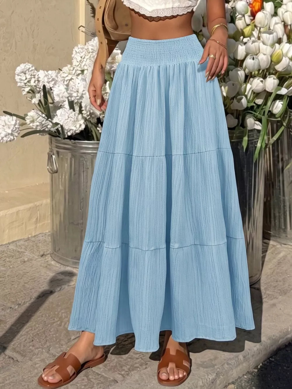 Blue smocked tiered maxi skirt with flowing fabric and textured detail.