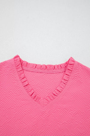 Women's pink textured V-neck blouse with ruffled neckline detail