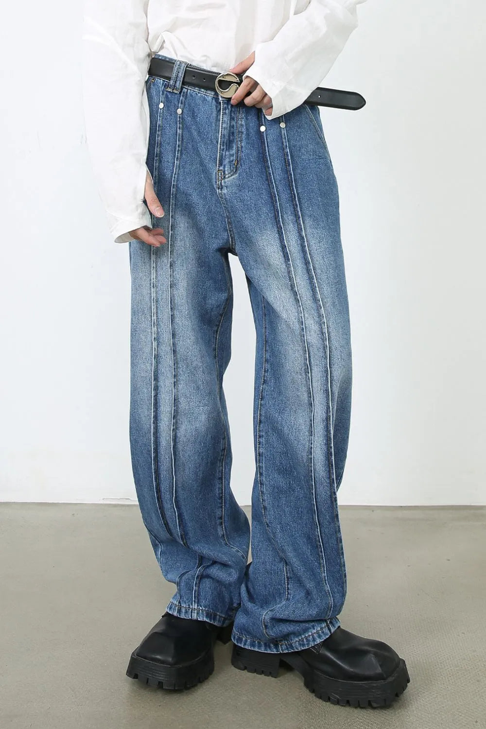 Medium wash denim trousers with vertical seams and a relaxed fit.