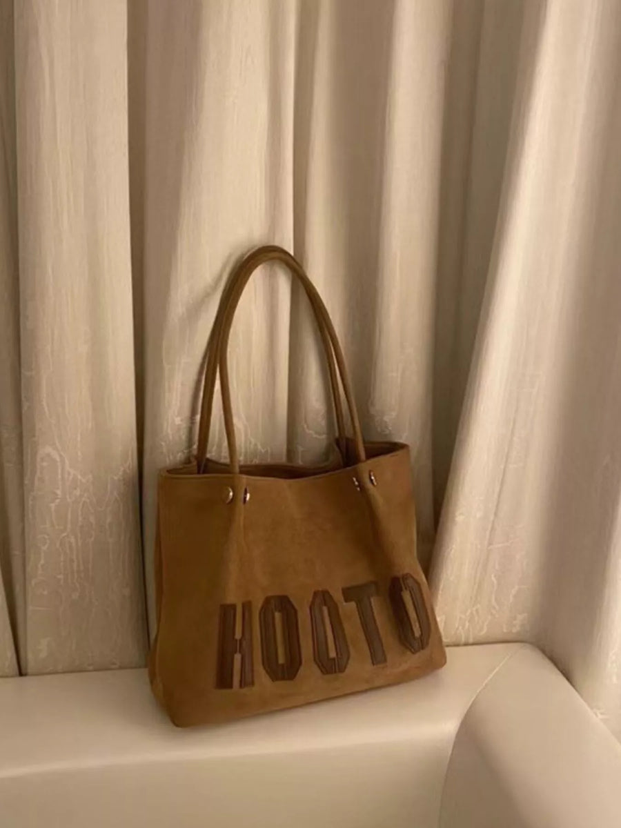 Brown PU leather tote bag with embossed lettering and double straps.
