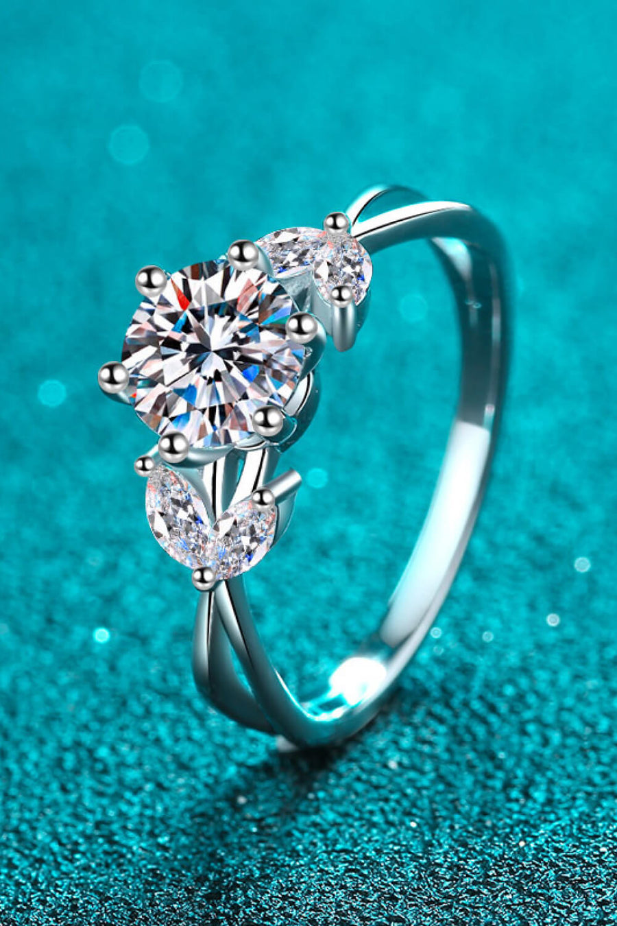Silver moissanite blossom ring with a central round cut stone and two marquise cut stones.