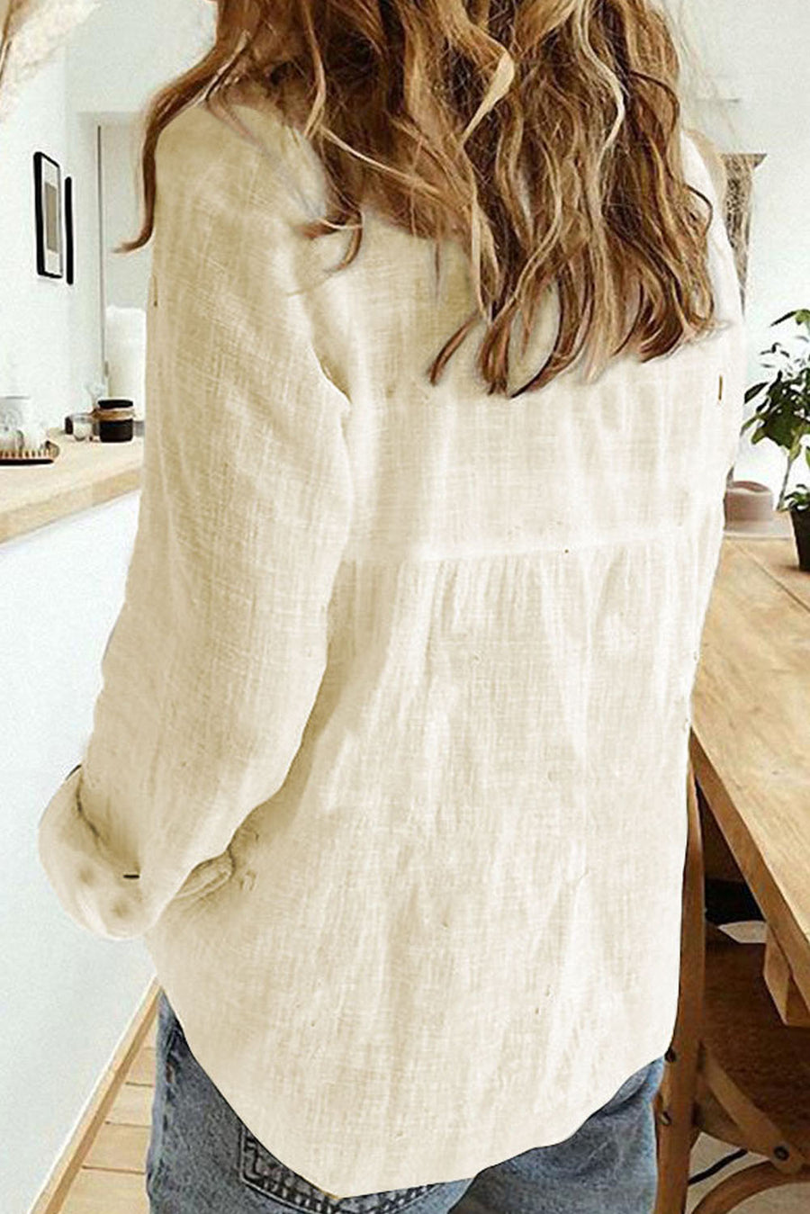 Ivory linen button-down blouse with relaxed fit and long sleeves.
