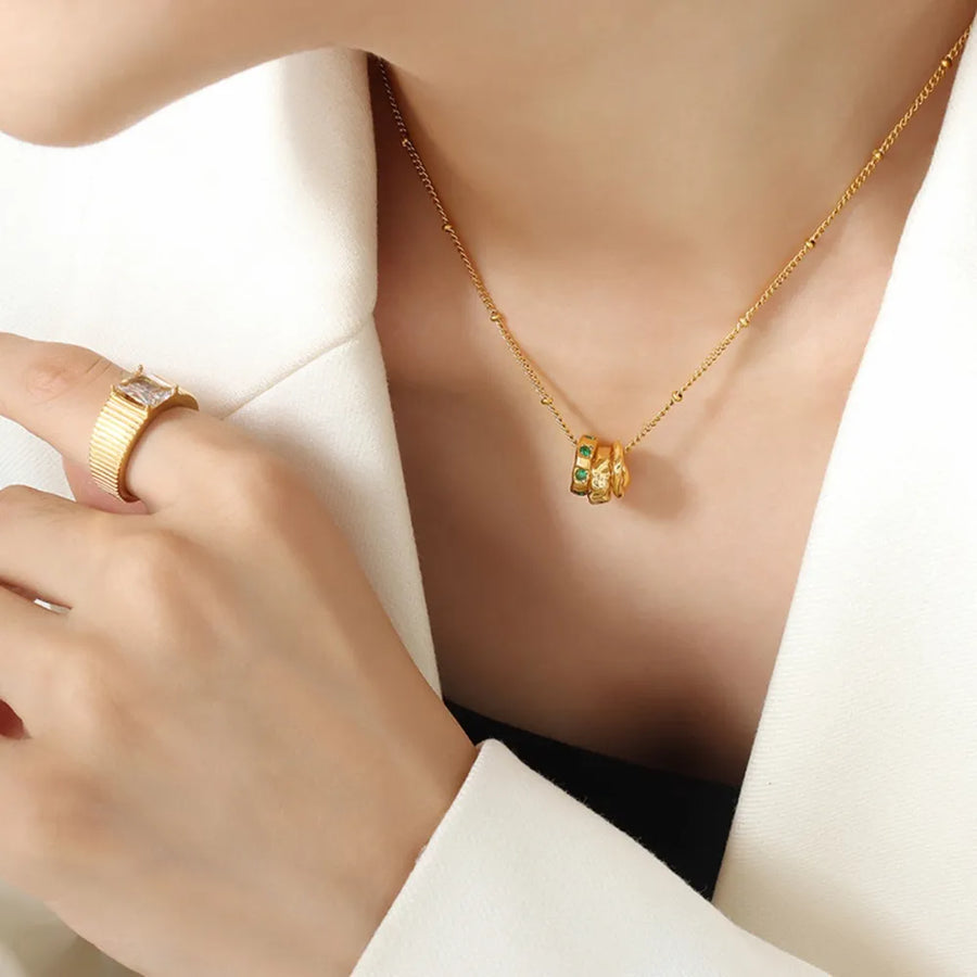 Gold necklace with interlocking circles featuring emerald stones and a beaded chain.