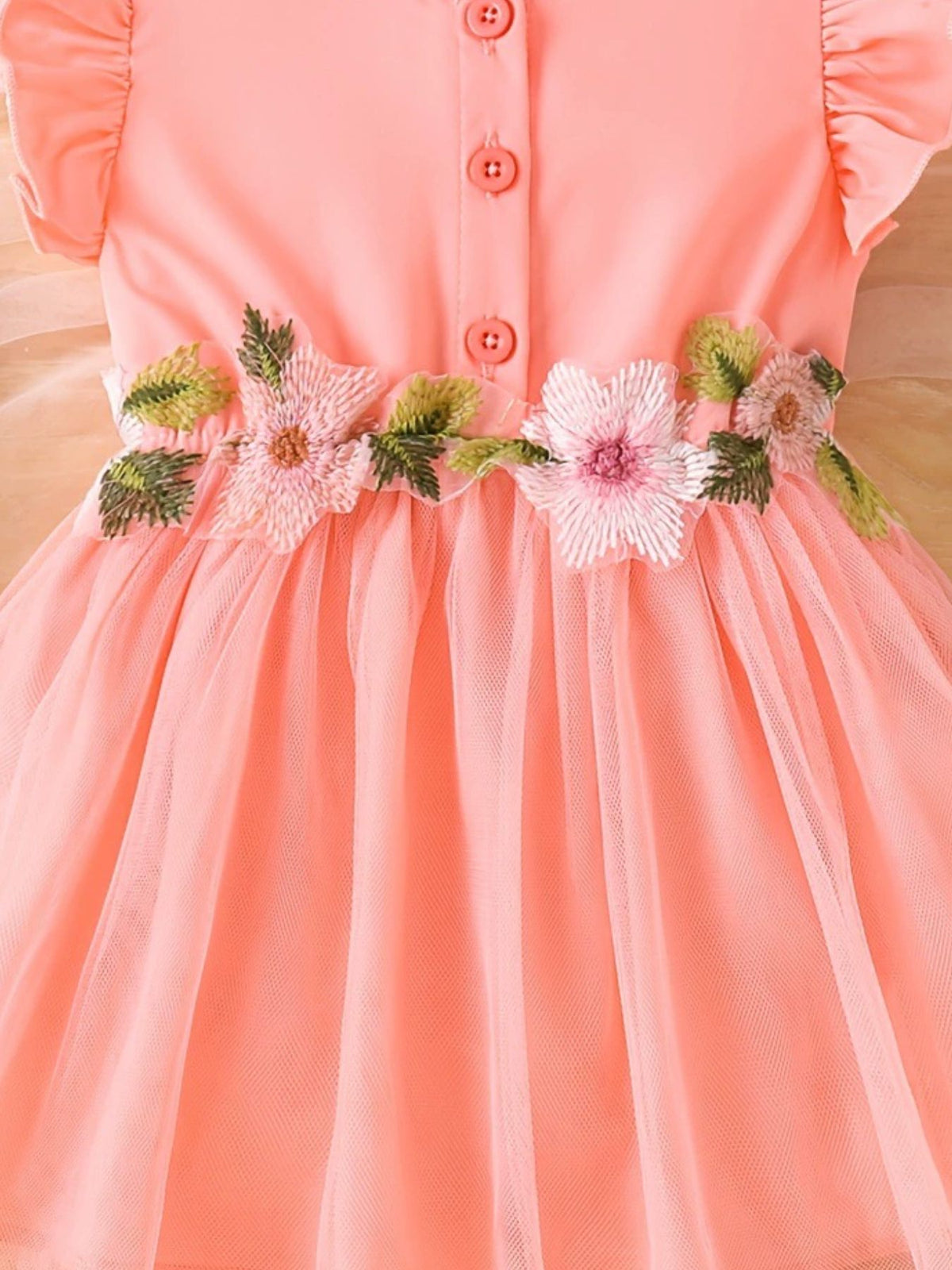 Watermelon pink baby dress with floral appliqué belt and ruffle sleeves.