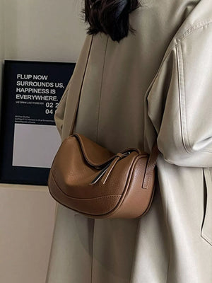 Brown pebbled leather crossbody bag with flap closure and tassel detail