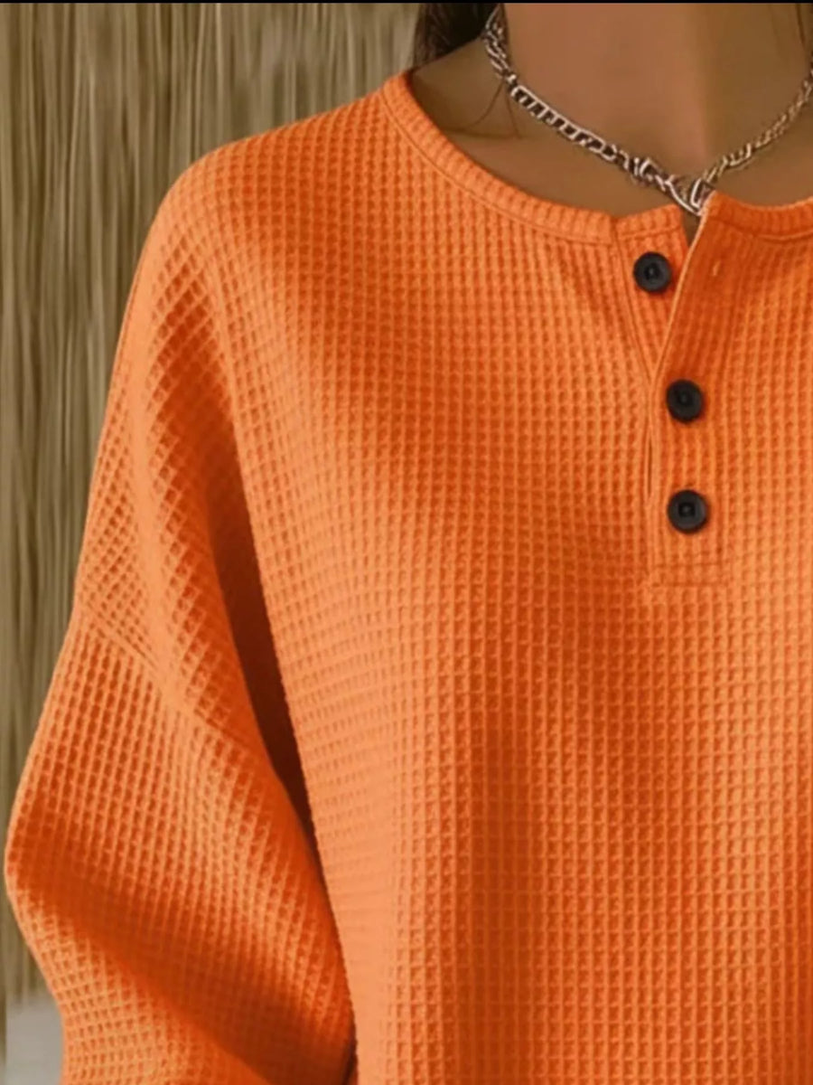 Orange waffle knit button detail top with crew neck and long sleeves.