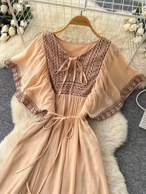 Peach embroidered V-neck maxi dress with tie detail and flutter sleeves.