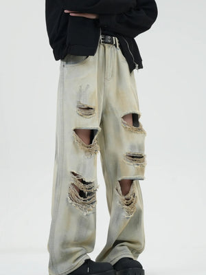 Distressed wide-leg jeans in Yellow Mud with heavy rips and a faded wash.