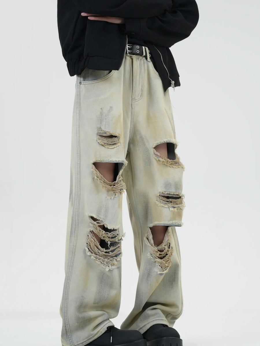 Distressed wide-leg jeans in Yellow Mud with heavy rips and a faded wash.