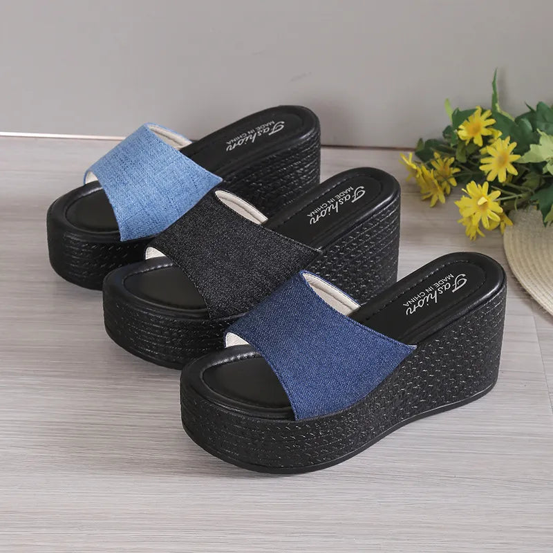 Denim platform wedge slides in dark blue and black with open toe and thick sole.