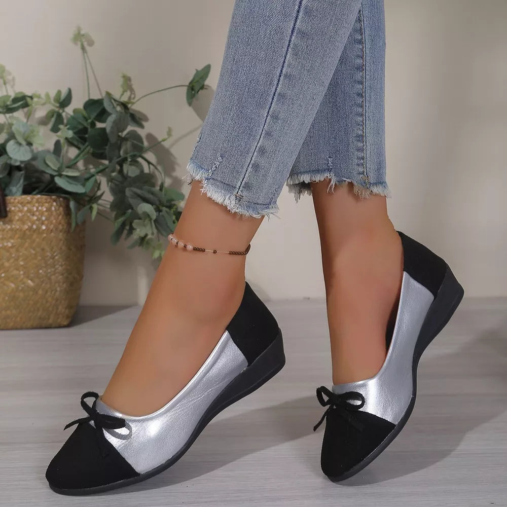 Black and silver bow-embellished slip-on flats with a low wedge heel.