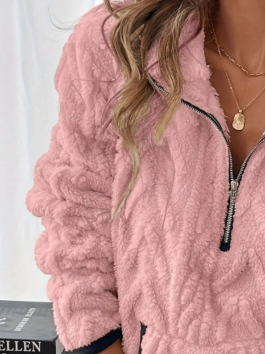 Pink sherpa half zip sweatshirt with textured sleeves and black zipper detail.