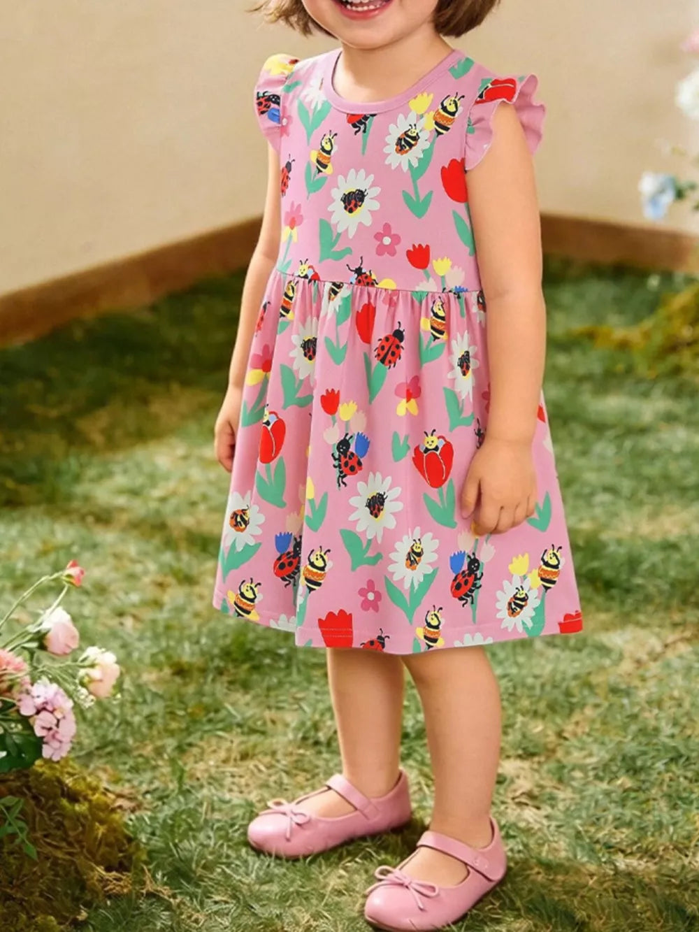 Pink cotton toddler dress with ruffle sleeves and a floral, ladybug, and bee print.