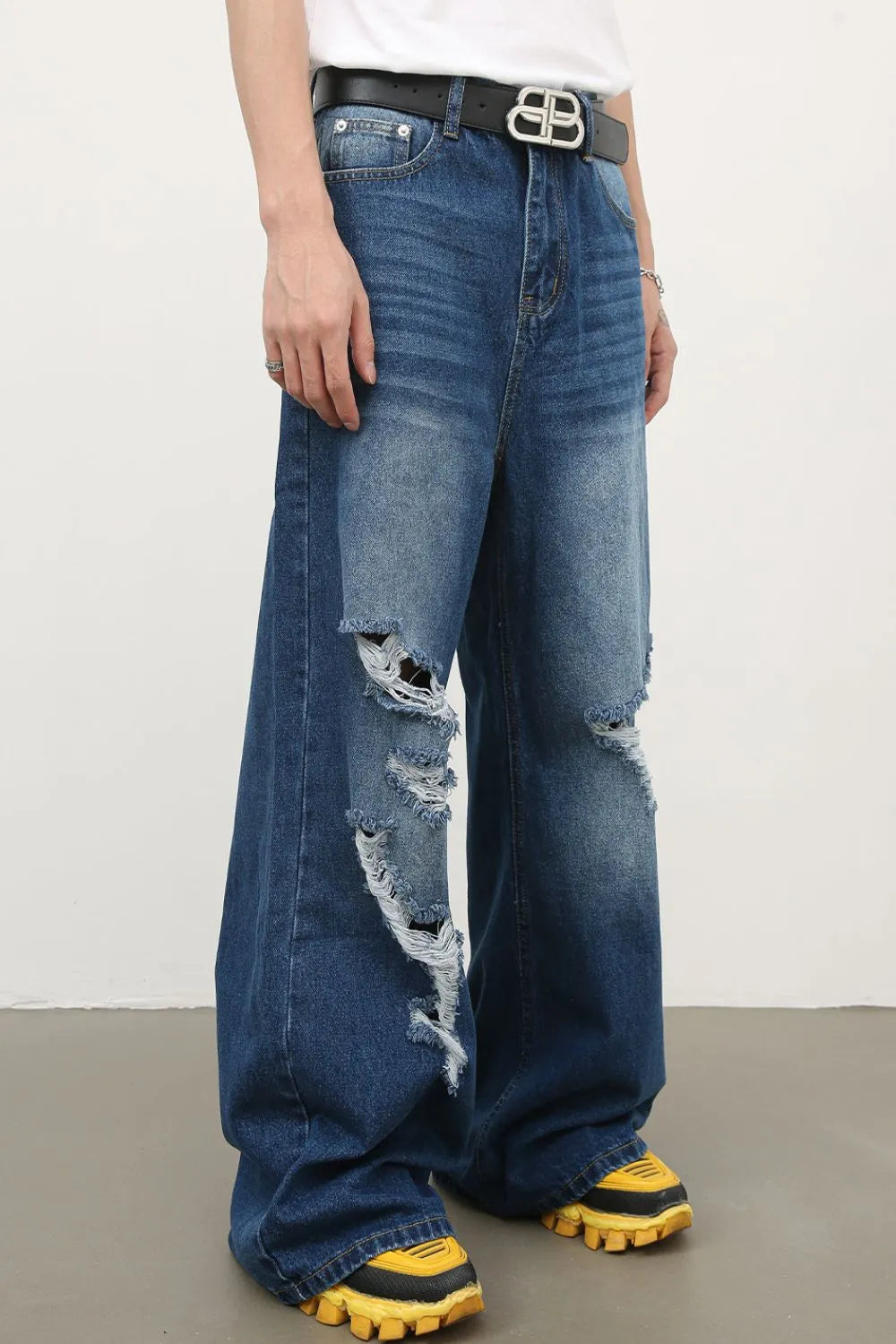 Distressed palazzo jeans in medium wash denim with ripped details and a faded hem.