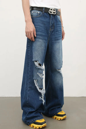 Distressed palazzo jeans in medium wash denim with ripped details and a faded hem.