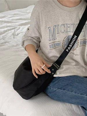 Black crossbody bag with adjustable strap featuring white text.