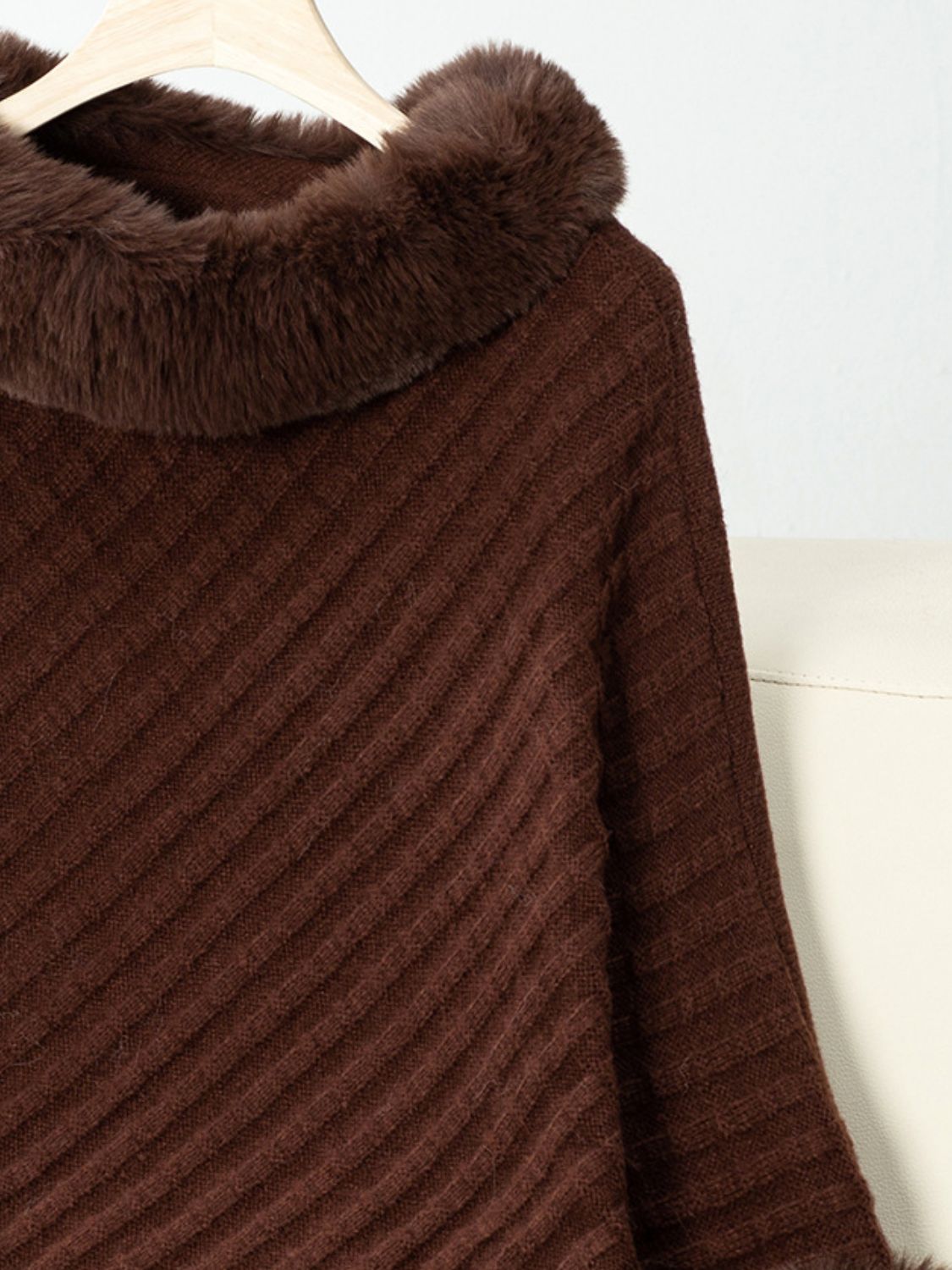 Chocolate knit poncho with faux fur trim and diagonal ribbing detail.