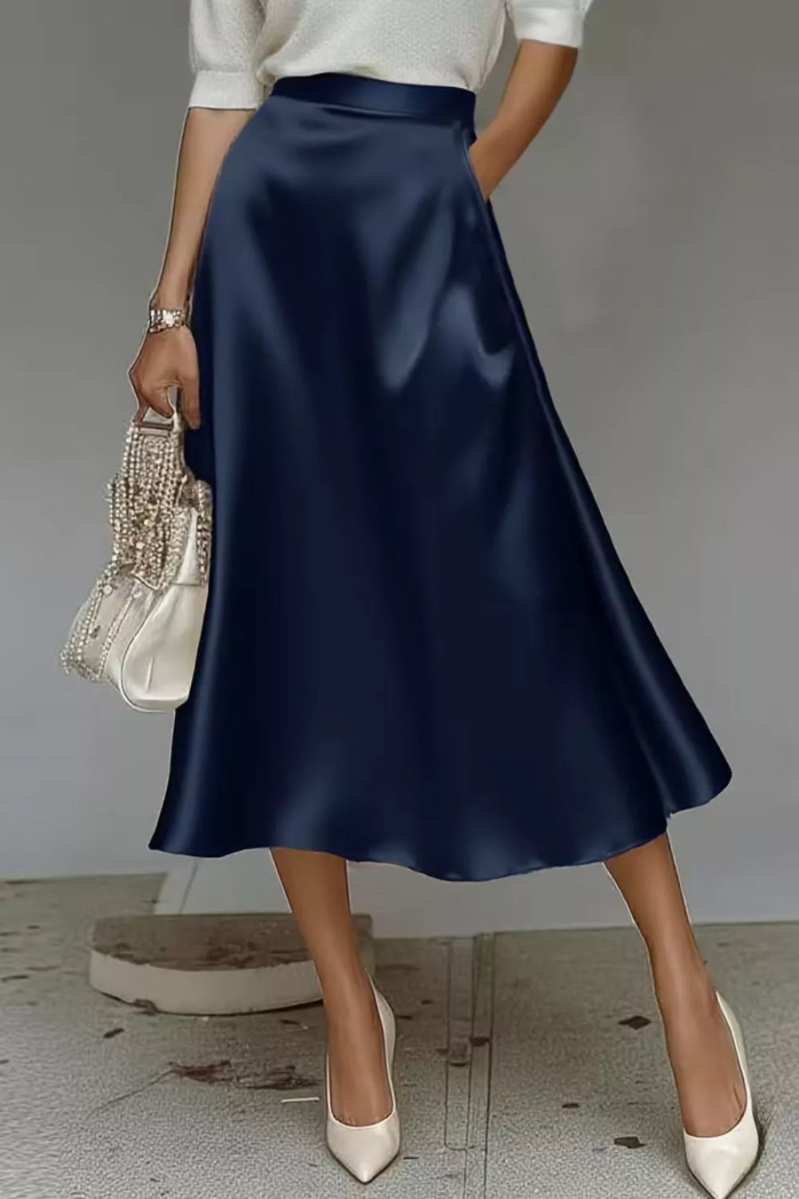Navy satin a-line midi skirt with hidden pockets, shown with a white top and heels.