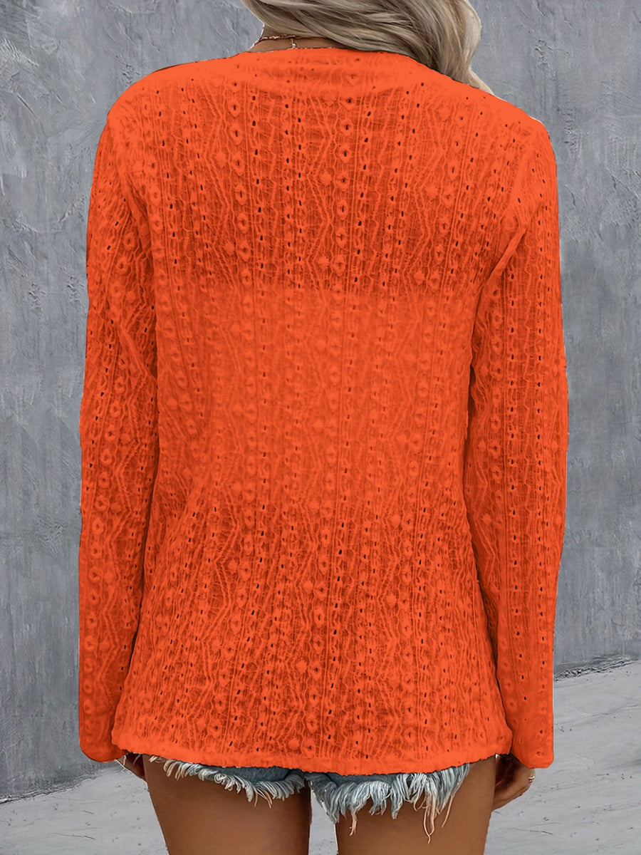 Orange open-weave long sleeve cardigan with a draped front and intricate pattern.