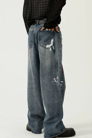 Artisan paint-splatter baggy jeans in medium wash denim with artistic paint details.