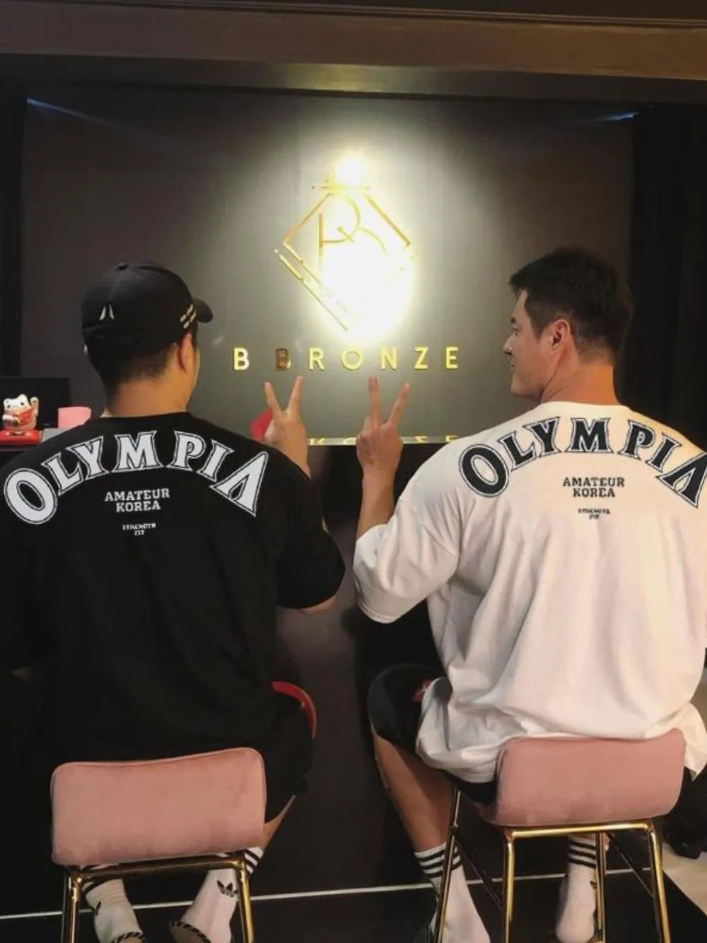 Oversized graphic t-shirts in black and white with "Olympia Amateur Korea" print on back.