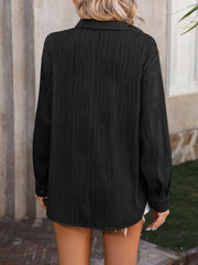 Black oversized button-down shirt with textured pleats and long sleeves.