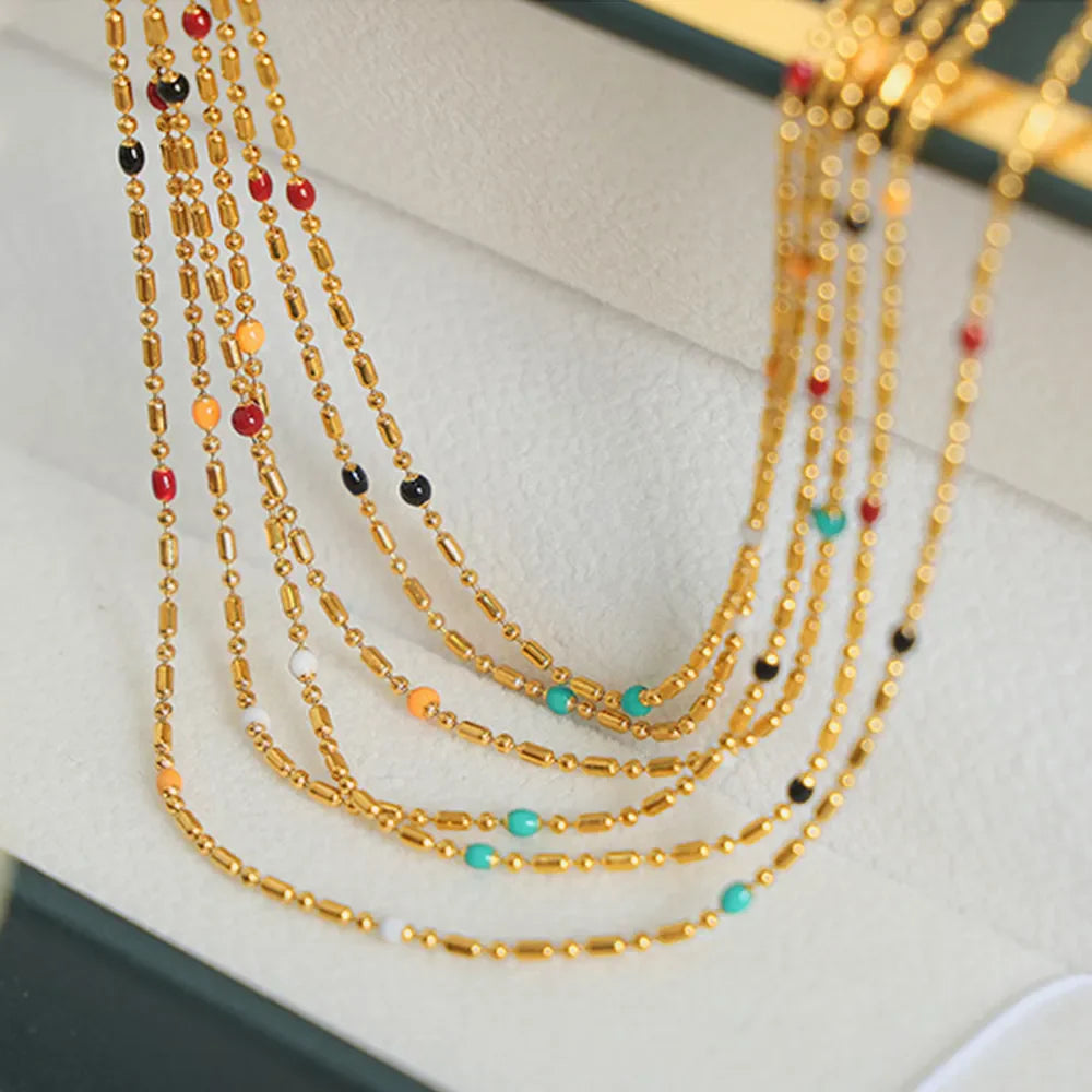 Gold necklace with colorful beads and barrel accents, layered style