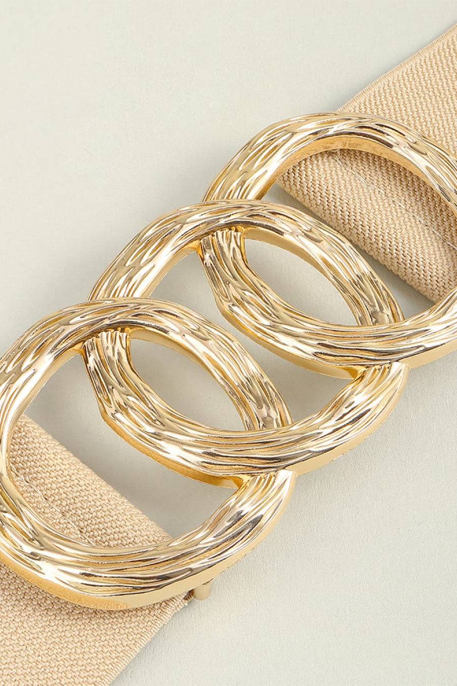 Tan elastic belt with textured gold triple ring buckle detail