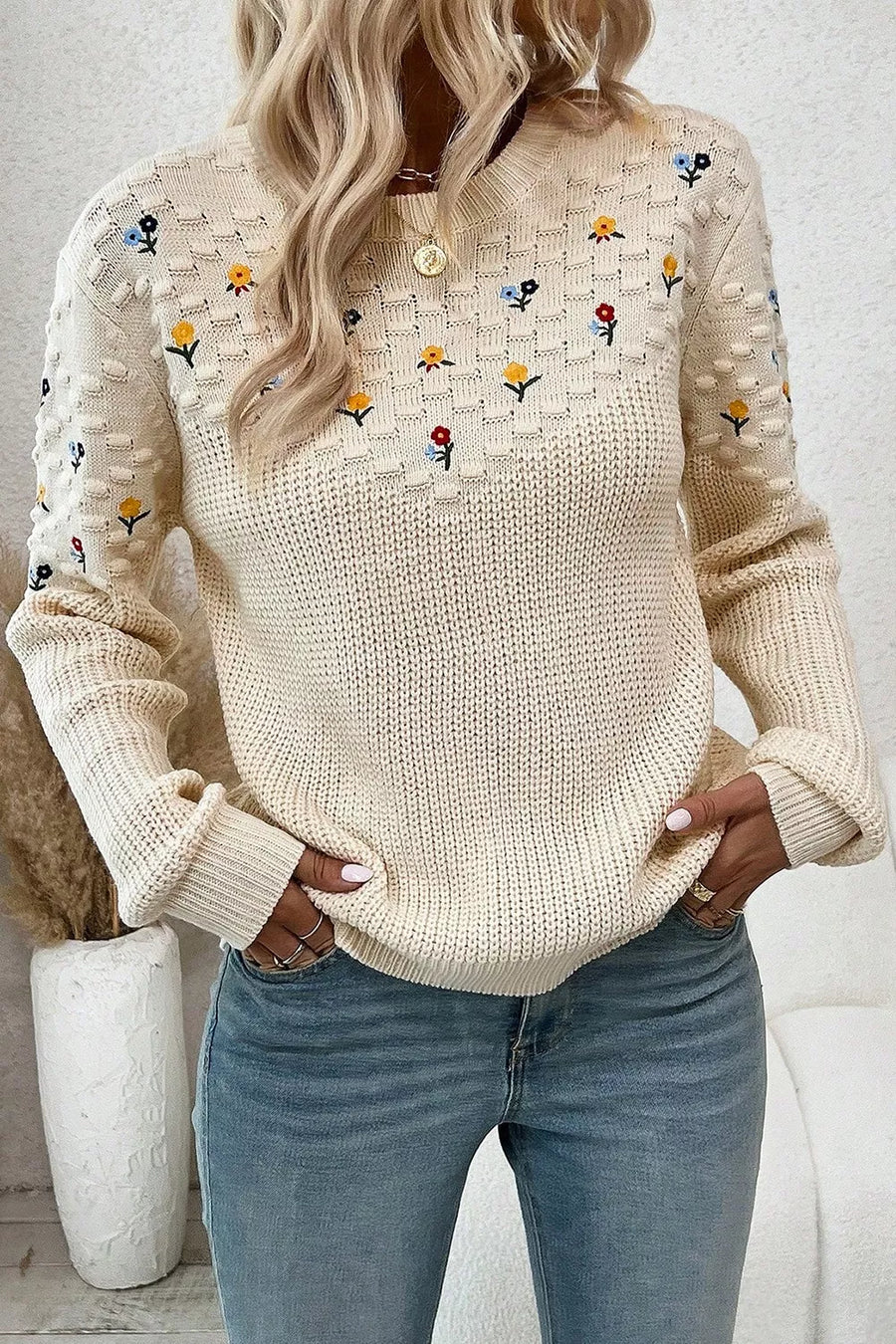Beige embroidered round-neck sweater with dropped shoulders and textured sleeves.