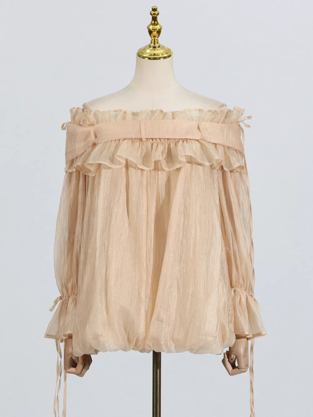 Romantic off-shoulder ruffled blouse in champagne color with billowy sleeves and adjustable ties.