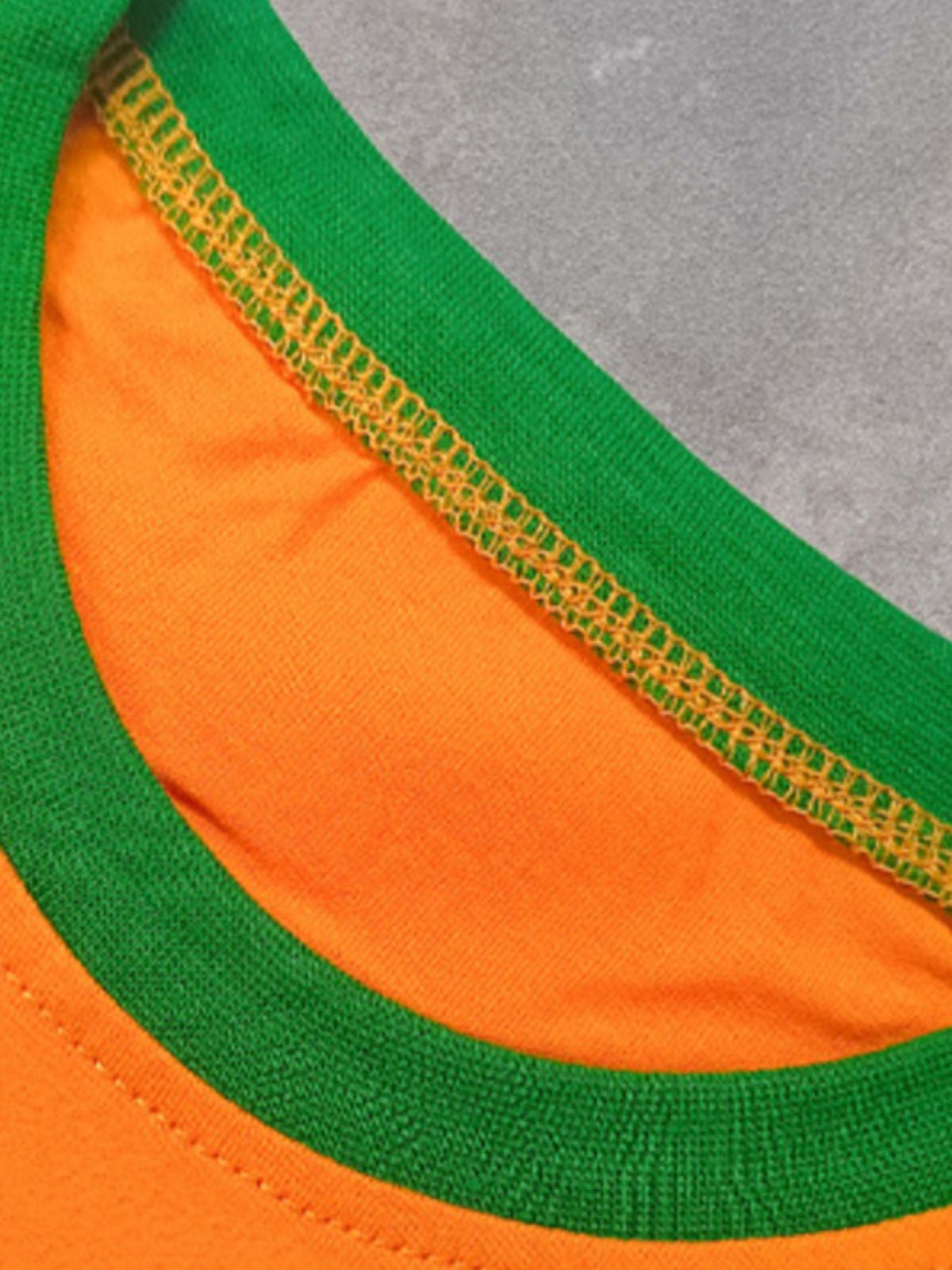 Orange cotton crew neck t-shirt with green trim and yellow stitching detail.