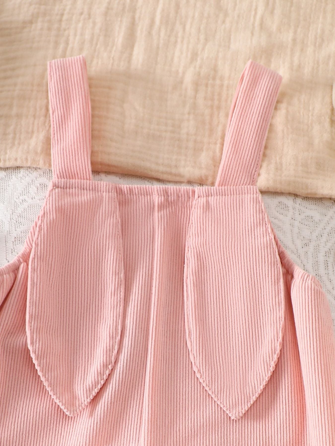 Pink corduroy baby one-piece with bunny ear details on the straps.