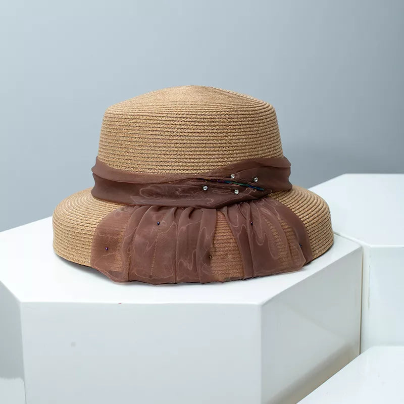 Wheat straw cloche sun hat in beige with a sheer brown ribbon and jeweled accent.