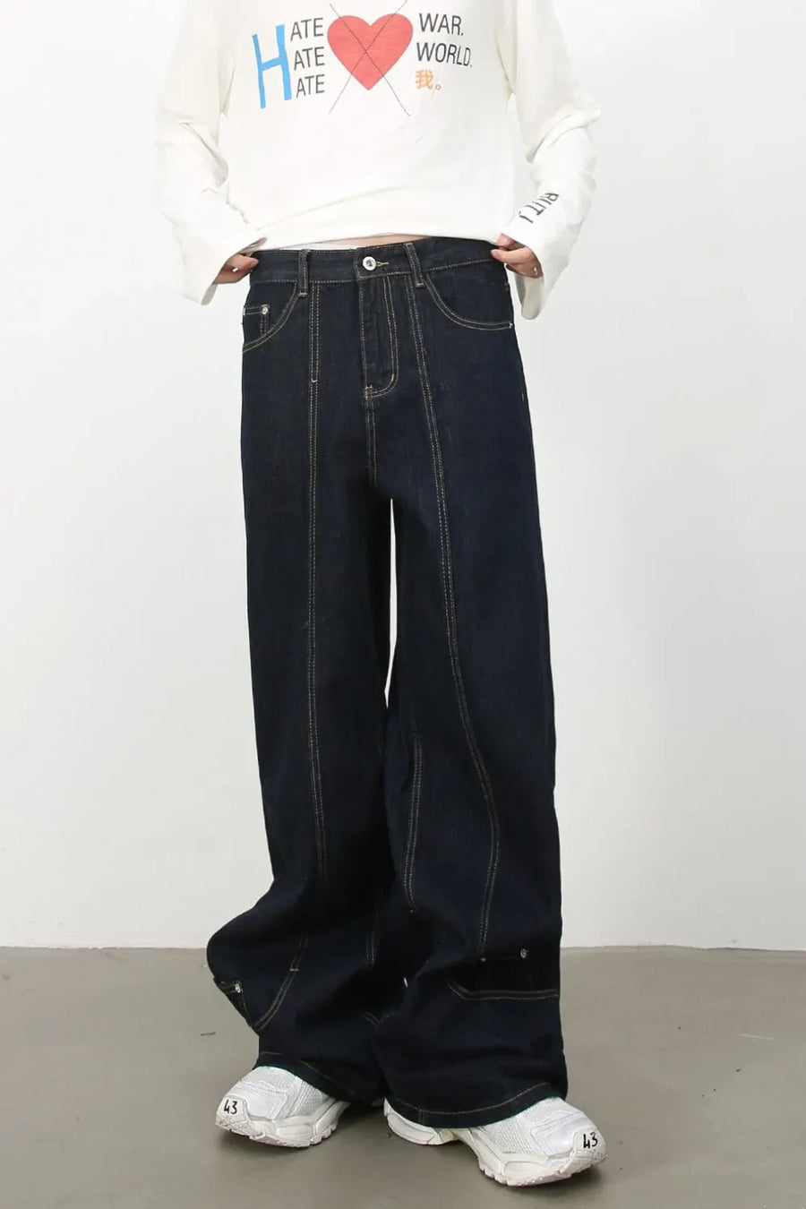 Dark denim trousers with sculptural seam details and contrast stitching.