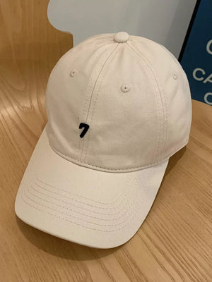 Beige cotton baseball cap with embroidered black number 7 detail.
