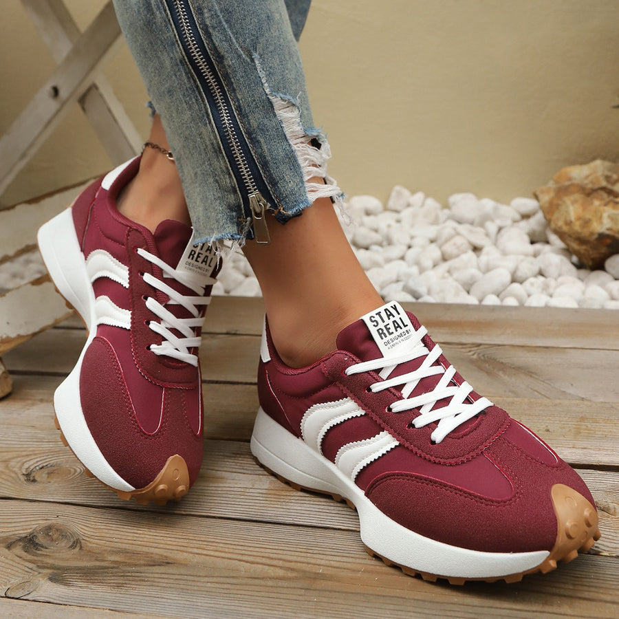 Maroon lace up round toe sneakers with white stripes and chunky sole.