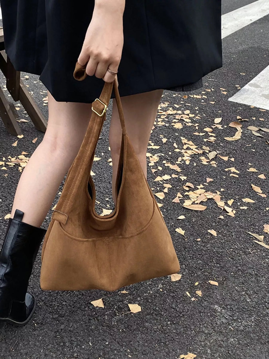 Large brown suede shoulder bag with gold buckle detail.